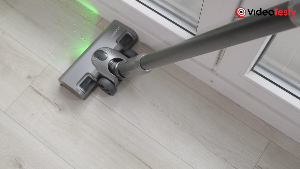 Sprzątanie brudów z pomocą UWANT V600. Elektroszczotka zbiera kukurydziane płatki przy drzwiach balkonowych