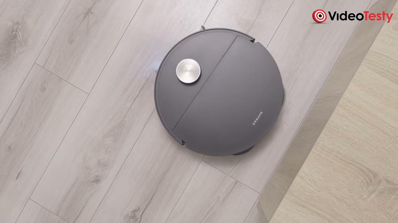 Czarny okrągły robot widziany od góry na jasnych panelach koło stolika