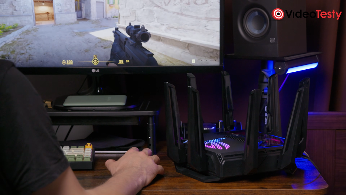 Spojrzenie z oddali na mężczyznę grającego na monitorze w CS:GO 2 obok czarnego routera
