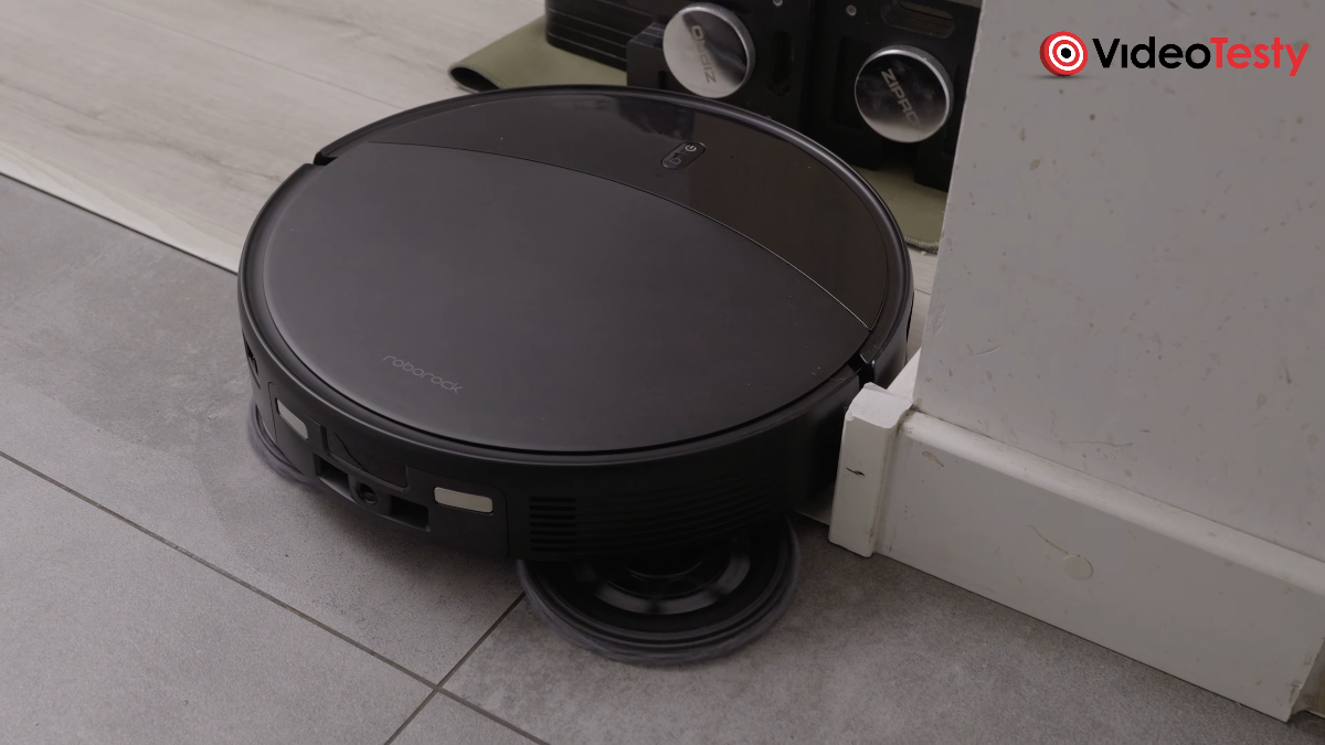 Czarny okrągły robot czyści podłogę przy hantlach