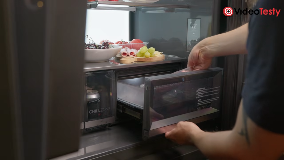 Mężczyzna wkłada jedzenie do środka szuflady Nutri Bank wewnątrz ciemnej lodówki
