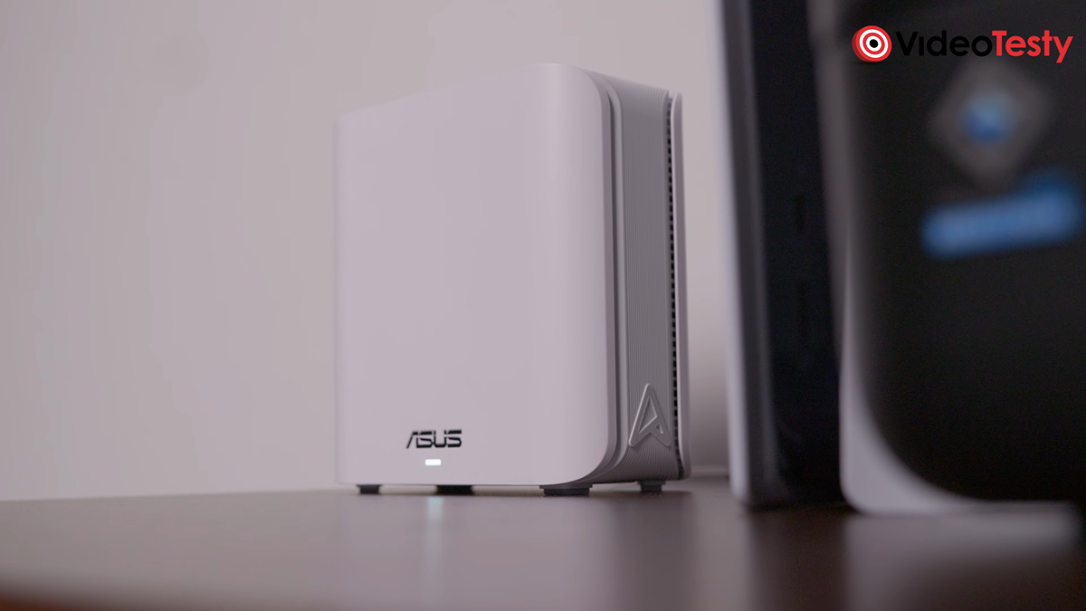 Spojrzenie na biały router na brązowej szafce. Stoi koło konsoli PS5