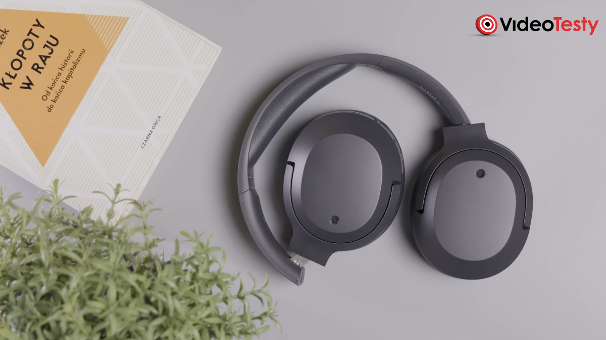 Złożone czarne słuchawki Edifier W820NB Plus V25 na szarym tle, koło książki i zielonej sztucznej rośliny