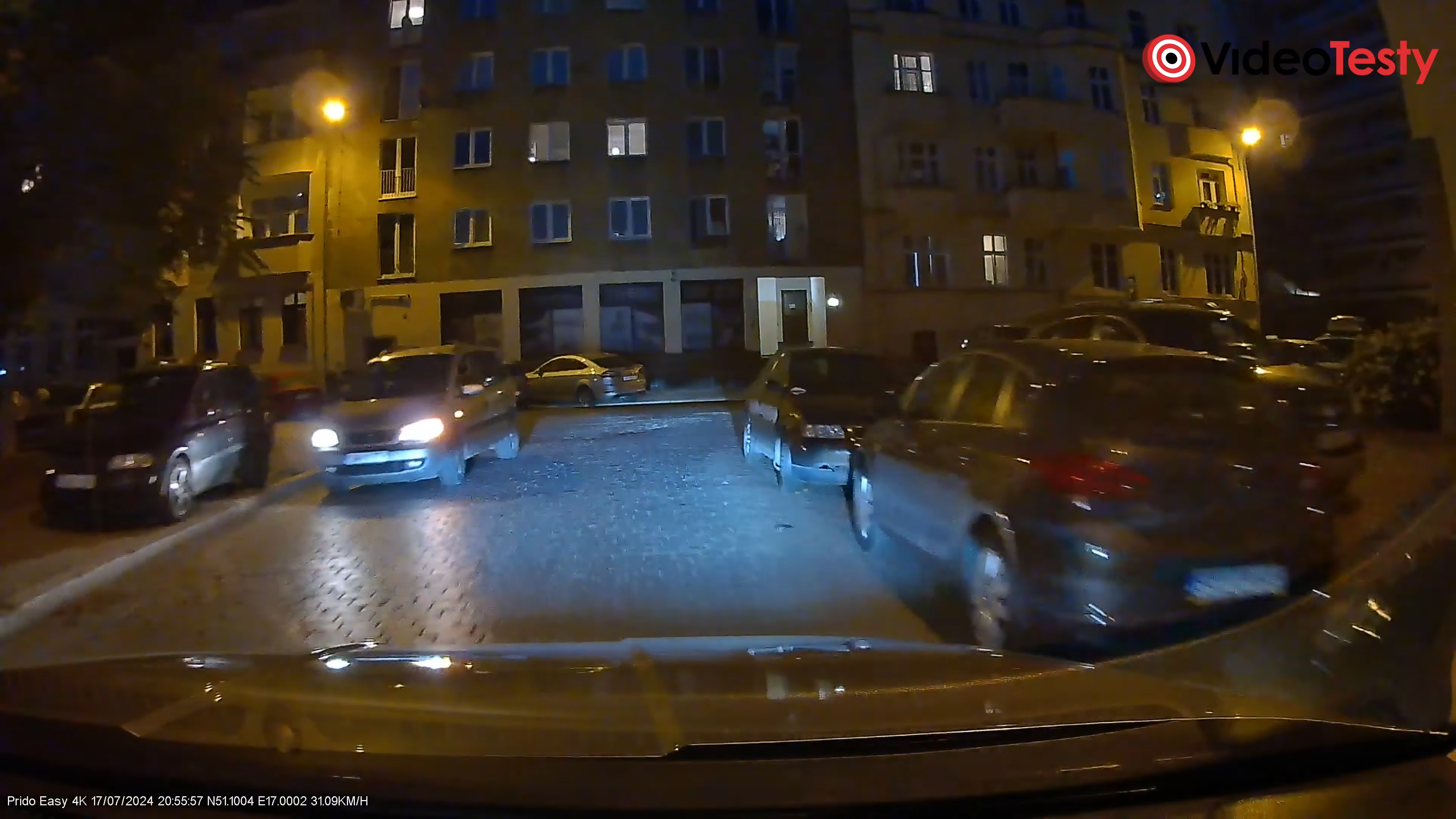 Nocne ujęcie kamery Prido Easy 4K. Widać mało szczegółów, jest dość ciemno, a samochód jadący z naprzeciwka ma niewyraźną tablicę rejestracyjną