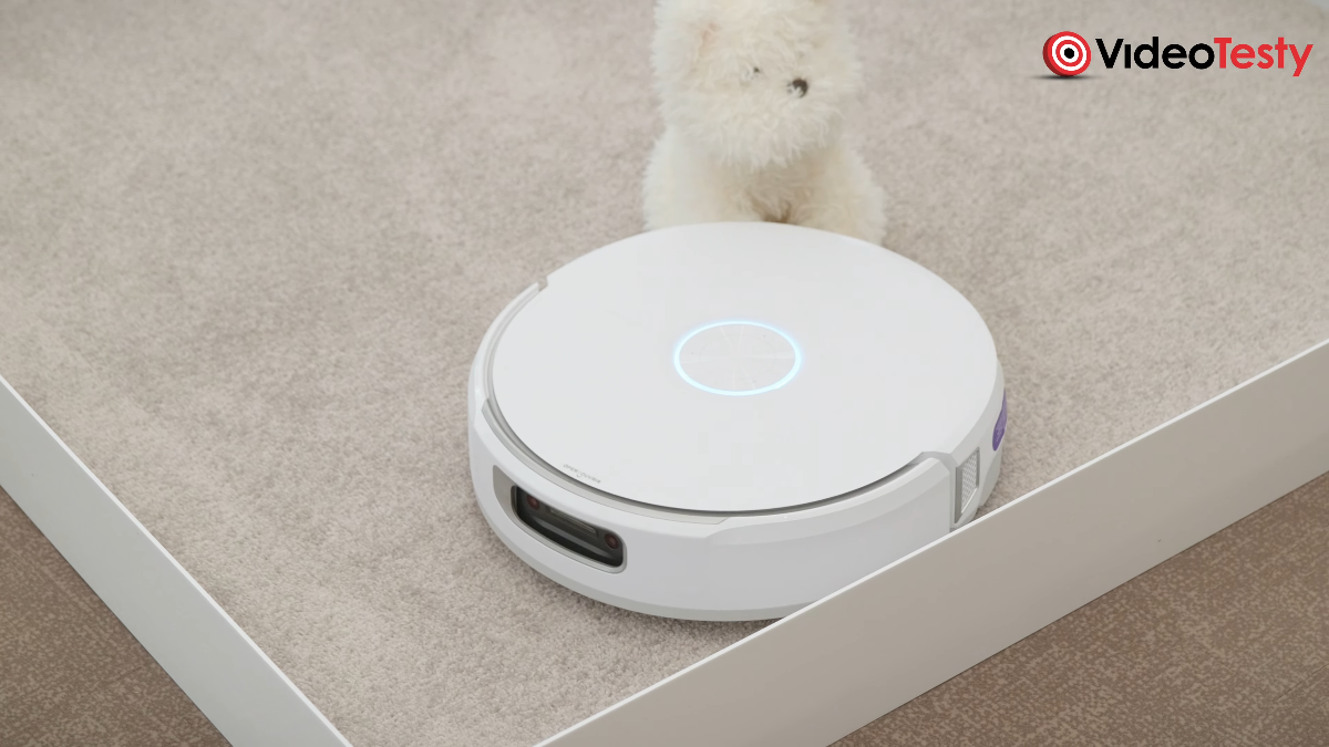 Biały robot Narwal Flow na dywanie koło pluszowego psa