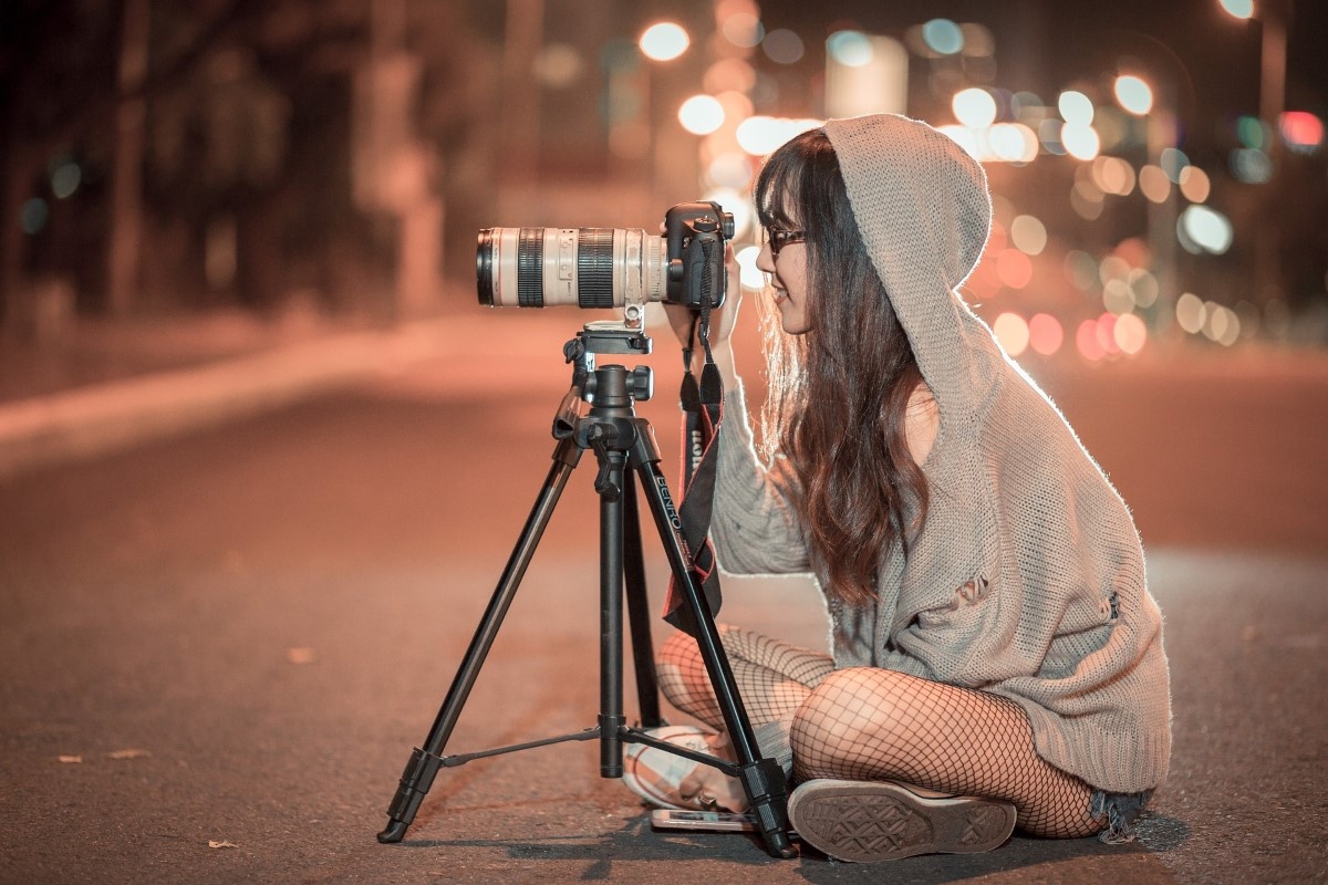 Fotografka siedzi nocą na ulicy przed statywem