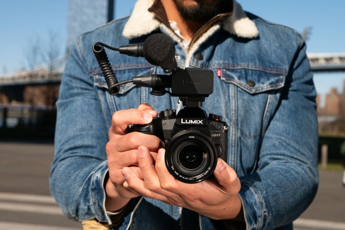 Kamera Lumix GH7 z adapterem DMW-XLR2 w rękach mężczyzny w kurtce dżinsowej
