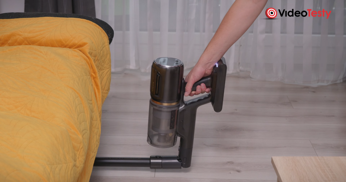 Wjazd pod sofę Dreame Z30 Ultra Sofa ma żółtą narzutę, a odkurzacz jesz szaro-czarny