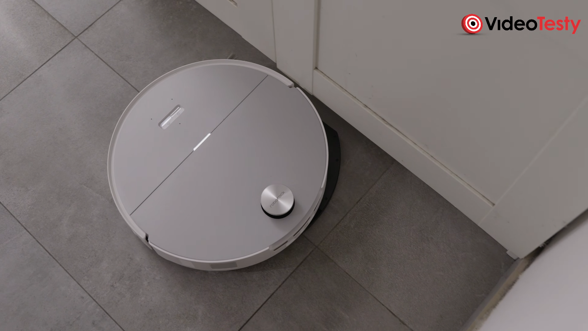 Biały robot przy krawędzi ściany na szarych kafelkach