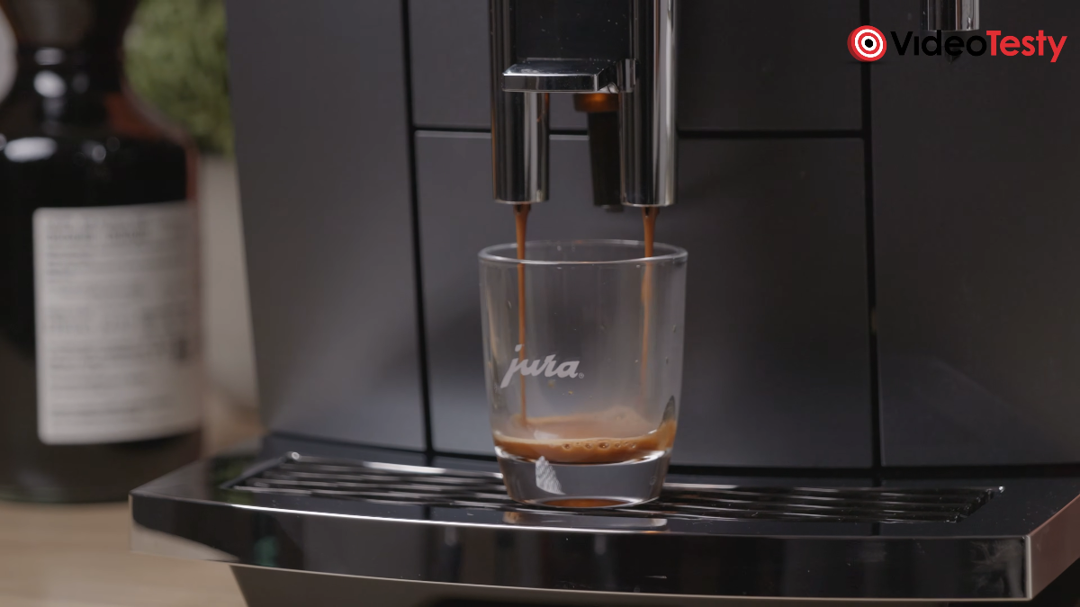 Nalewanie espresso do jednej niskiej szklanki w ciemno-srebrnym ekspresie